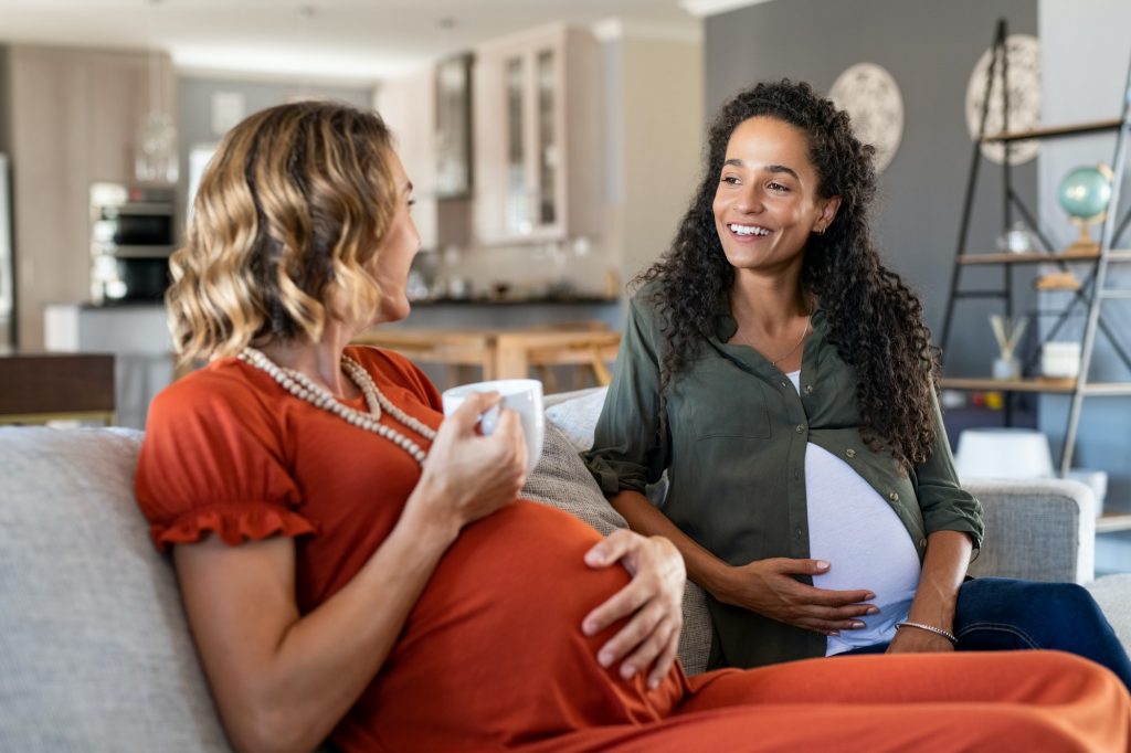 Pregnant women friends talking on sofa